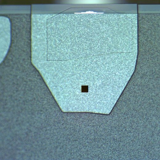 A Hitachi disk drive slider under the microscope, the square measuring aperture on its surface